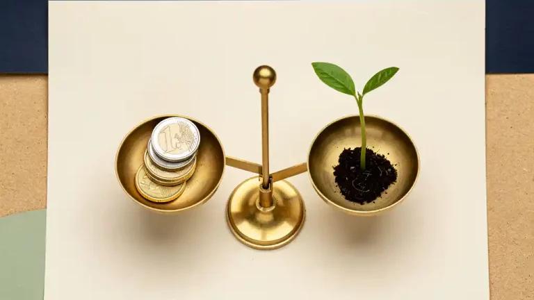 Messing weegschaal met euromunten tegenover een jong plantje op crèmekleurig oppervlak, symbool voor duurzame financiële groei.