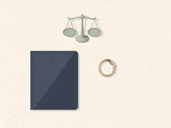 Gebarsten trouwring naast een gesloten documentmap en een klein weegschaaltje op een crèmekleurig bureau, symbool voor eerlijke boedelscheiding bij echtscheiding.